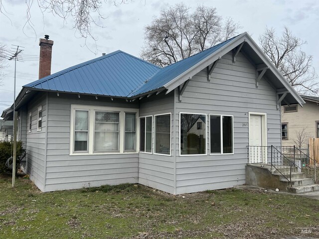 back of house featuring metal roof and a chimney