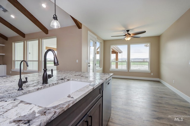 kitchen featuring light stone counters, dishwasher, hanging light fixtures, sink, and lofted ceiling with beams