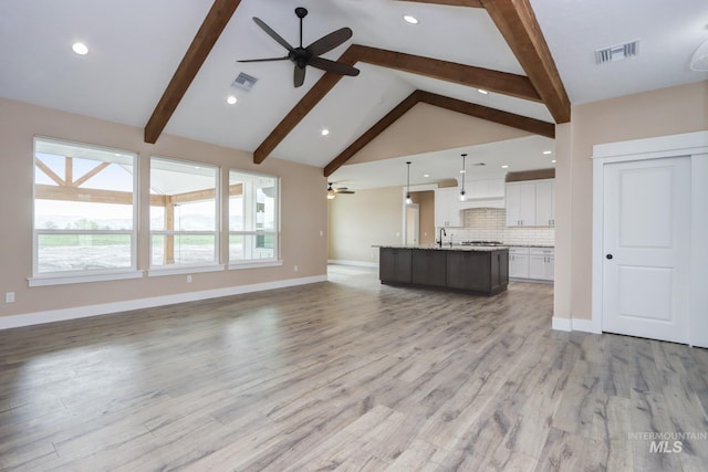 unfurnished living room featuring high vaulted ceiling, beamed ceiling, ceiling fan, and light hardwood / wood-style floors