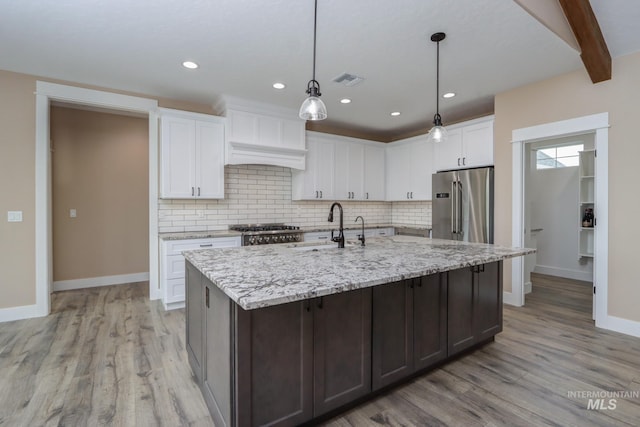 kitchen featuring stainless steel appliances, white cabinetry, sink, hanging light fixtures, and light wood-type flooring