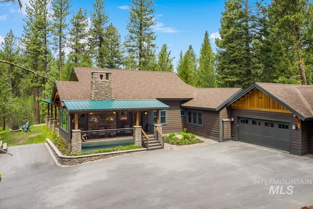 1460 Crown Point Pkwy, Cascade, ID 83611 - view of front of home featuring roof with shingles, driveway, stone siding, a garage, and covered porch