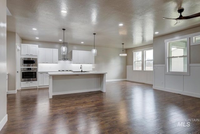 1113 W Blaine Ave, Nampa, ID 83651 - kitchen with light countertops, white cabinets, wall chimney exhaust hood, appliances with stainless steel finishes, and a sink