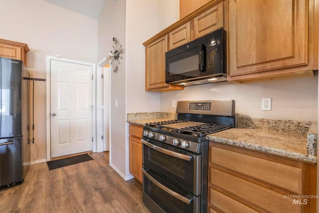 kitchen featuring light stone countertops, appliances with stainless steel finishes, and dark hardwood / wood-style flooring