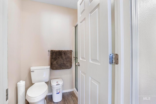 bathroom with walk in shower, toilet, and hardwood / wood-style flooring