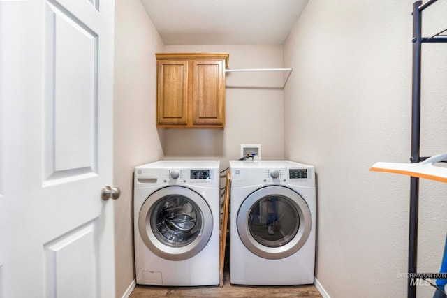 laundry area with cabinets, light wood-type flooring, and washing machine and clothes dryer