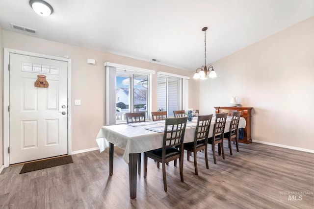 dining space featuring dark hardwood / wood-style flooring and an inviting chandelier