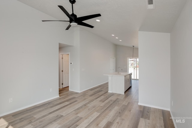 empty room featuring ceiling fan with notable chandelier, a textured ceiling, high vaulted ceiling, and light hardwood / wood-style floors