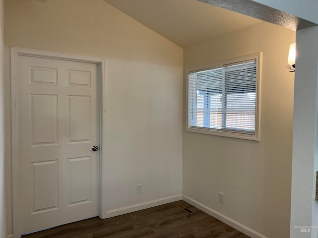 empty room with dark hardwood / wood-style flooring and vaulted ceiling