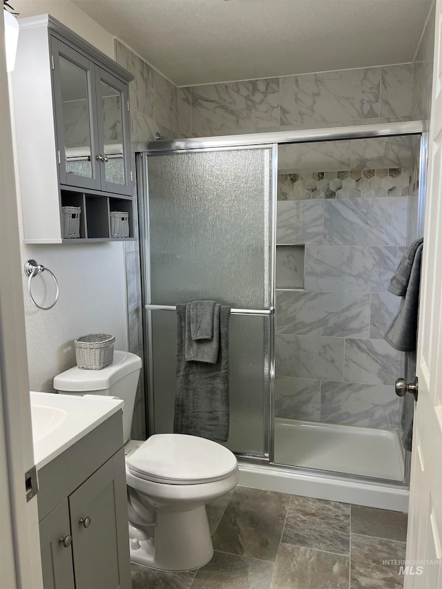 bathroom featuring an enclosed shower, vanity, tile floors, and toilet