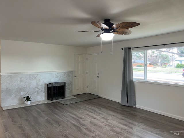 unfurnished living room featuring a fireplace, ceiling fan, and dark hardwood / wood-style flooring