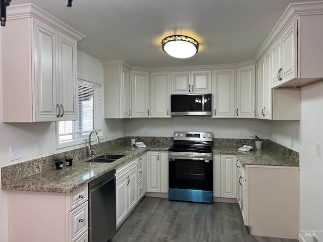 kitchen featuring sink, appliances with stainless steel finishes, dark wood-type flooring, stone counters, and white cabinetry