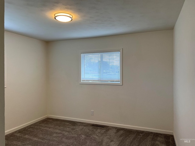 unfurnished room featuring dark carpet