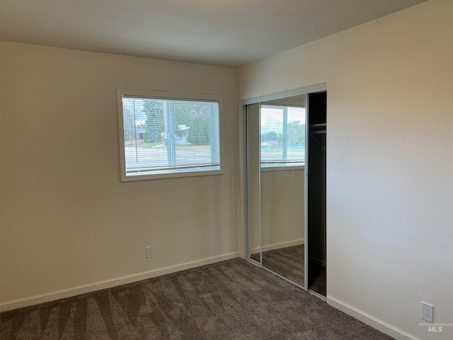 unfurnished bedroom featuring a closet and dark carpet