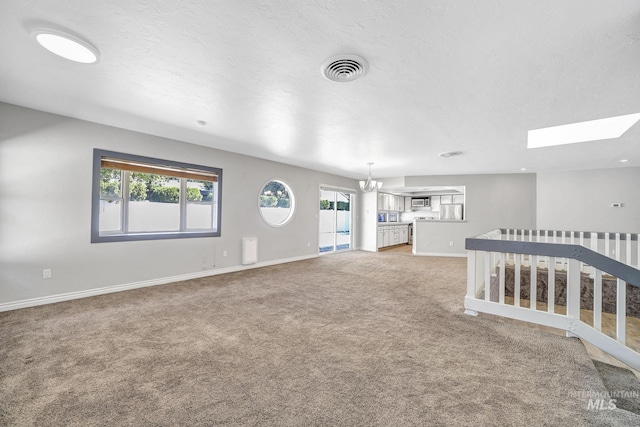 790 Academic Dr, Twin Falls, ID 83301 - unfurnished living room featuring baseboards, light carpet, a chandelier, visible vents, and a skylight