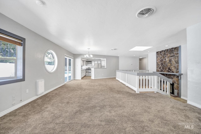 790 Academic Dr, Twin Falls, ID 83301 - unfurnished living room with baseboards, a chandelier, visible vents, a skylight, and light colored carpet