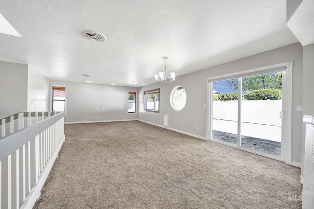 790 Academic Dr, Twin Falls, ID 83301 - unfurnished living room with visible vents, baseboards, an inviting chandelier, carpet, and a textured ceiling