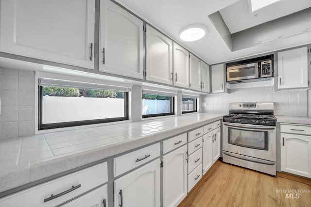 790 Academic Dr, Twin Falls, ID 83301 - kitchen with white cabinets, tasteful backsplash, light wood-style flooring, and appliances with stainless steel finishes