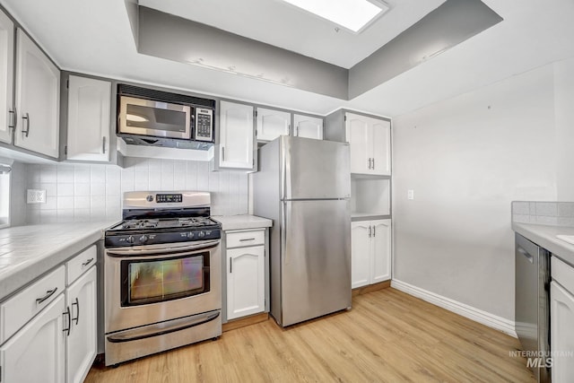 790 Academic Dr, Twin Falls, ID 83301 - kitchen with white cabinets, stainless steel appliances, light wood finished floors, baseboards, and backsplash