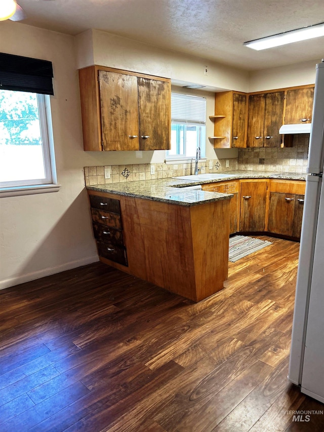 2320 S Illinois, Caldwell, ID 83605 - kitchen featuring dark wood-style floors, a peninsula, brown cabinetry, tasteful backsplash, and open shelves