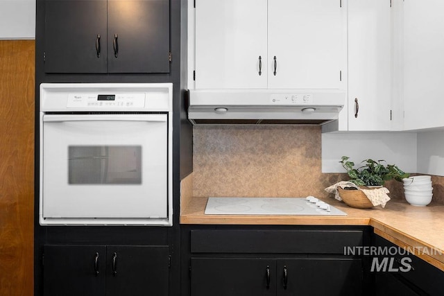 5928 W Grunder, Boise, ID 83709 - kitchen with white appliances, under cabinet range hood, backsplash, dark cabinets, and white cabinetry