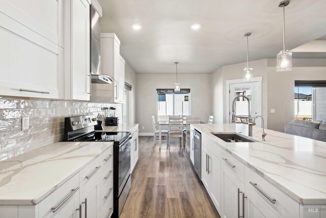 kitchen featuring decorative backsplash, light wood-style flooring, stainless steel appliances, white cabinetry, and a sink