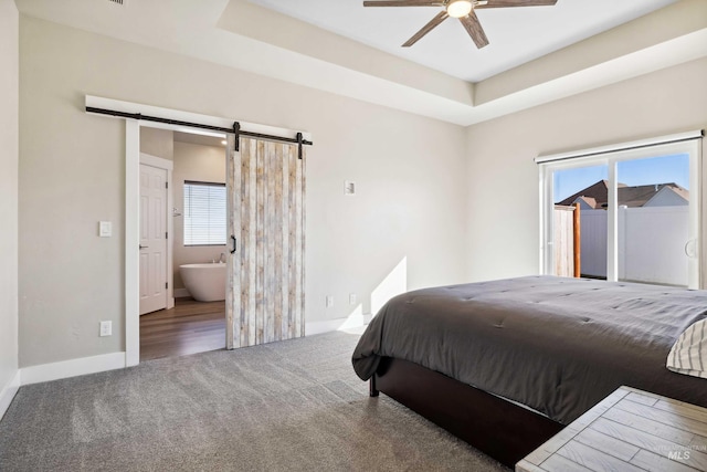 bedroom featuring a barn door, a raised ceiling, multiple windows, and carpet