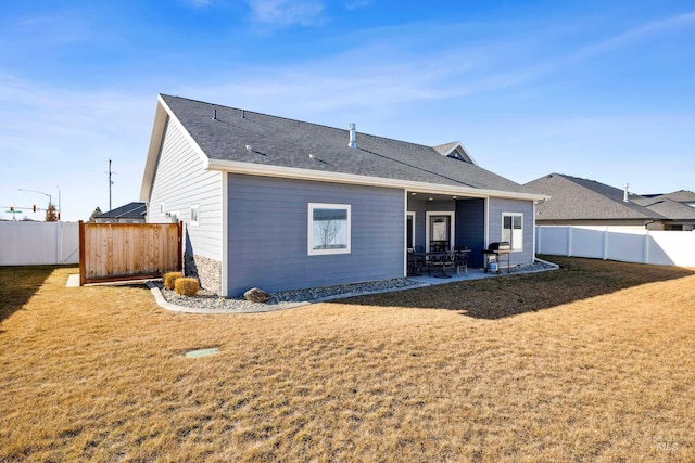 rear view of property featuring a yard, a patio area, a fenced backyard, and roof with shingles