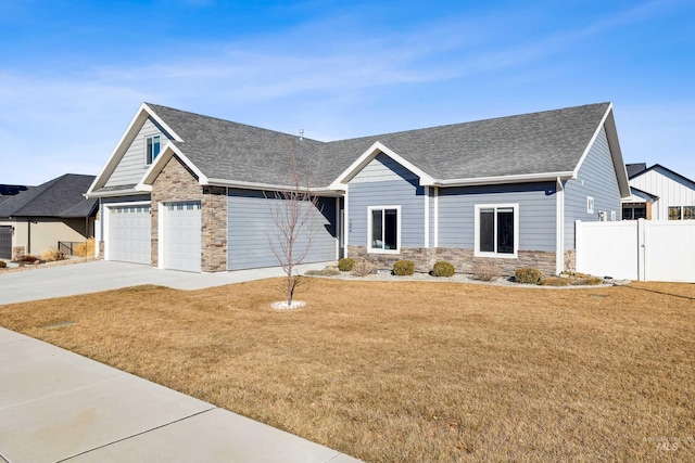 view of front facade with driveway, fence, stone siding, and roof with shingles