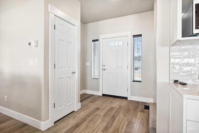 foyer with light wood-type flooring and baseboards