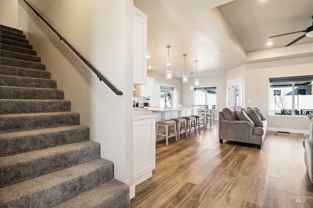 staircase with ceiling fan, baseboards, wood finished floors, and recessed lighting