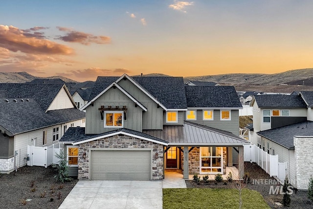 view of front of home featuring fence, concrete driveway, a garage, stone siding, and board and batten siding