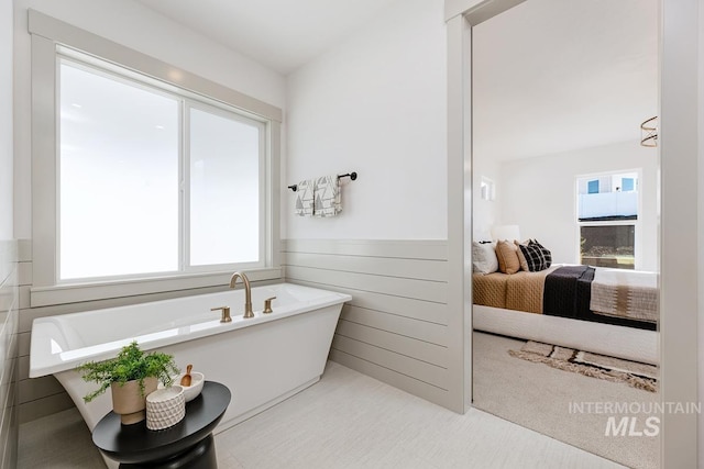 bathroom with a soaking tub, ensuite bath, wainscoting, and wood walls