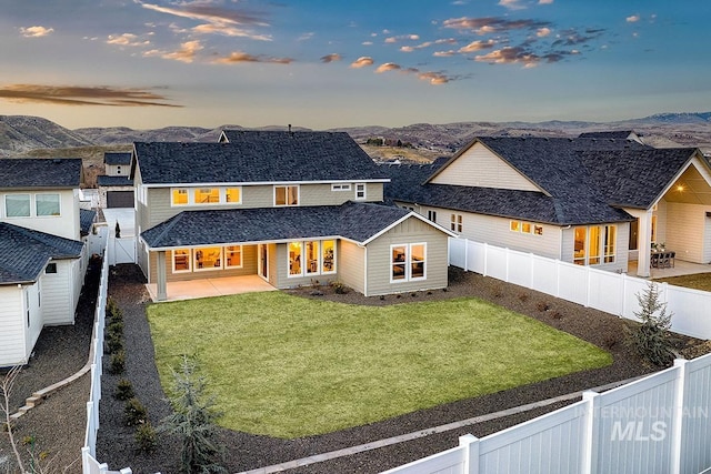 rear view of property featuring a patio area, a yard, a fenced backyard, and a mountain view