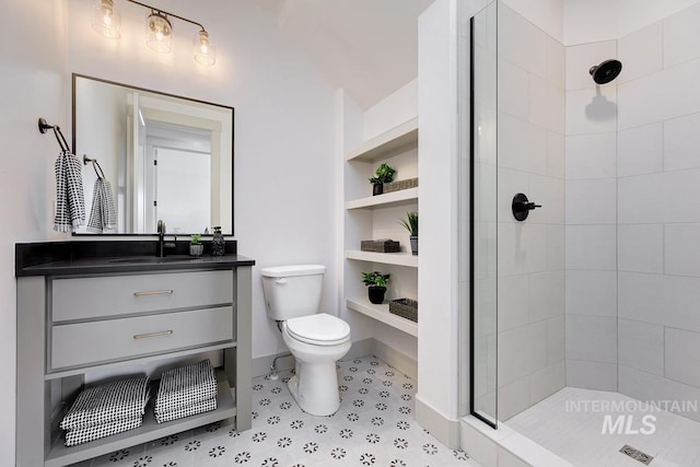 bathroom featuring vanity, built in shelves, a tile shower, tile patterned flooring, and toilet