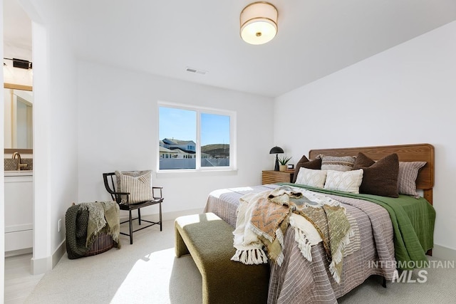 carpeted bedroom featuring a sink, visible vents, and baseboards