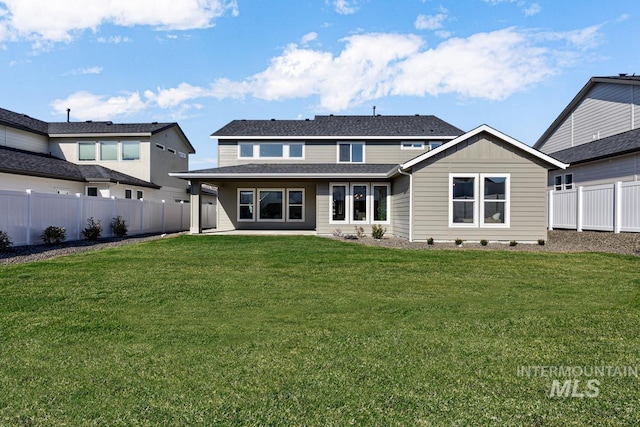 rear view of property with a yard and a fenced backyard