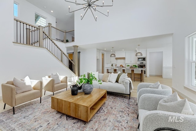 living room featuring a notable chandelier, stairway, a high ceiling, and baseboards