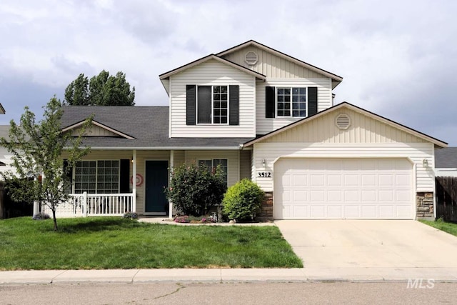 traditional-style house with a garage, driveway, covered porch, a front lawn, and stone siding