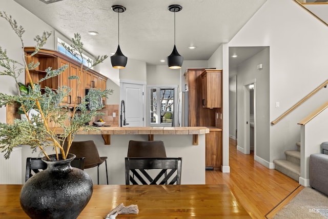 kitchen featuring a breakfast bar area, open shelves, a peninsula, plenty of natural light, and brown cabinets