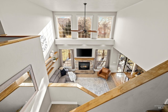 living area featuring a wealth of natural light, a fireplace, a high ceiling, and a ceiling fan