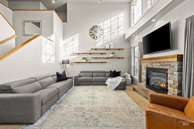 carpeted living room with a fireplace and a high ceiling