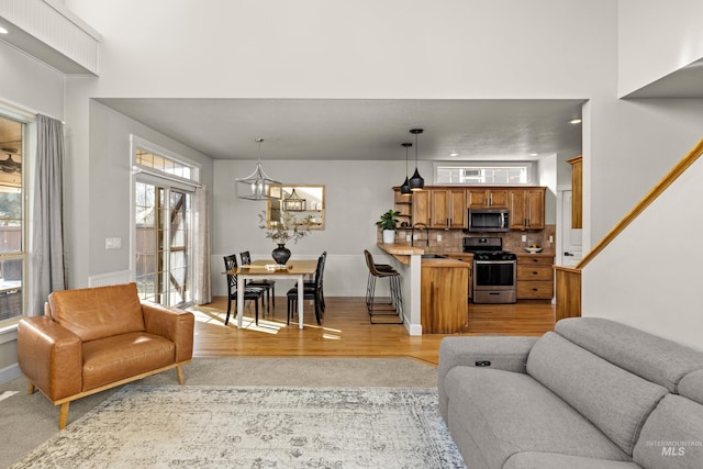 living area featuring a notable chandelier, light wood-style floors, and baseboards