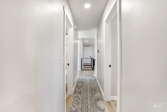 hall featuring light wood-style flooring, baseboards, and recessed lighting