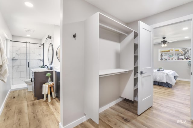 walk in closet with light wood-type flooring, ceiling fan, visible vents, and a sink