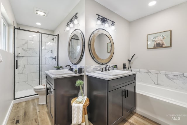 full bath featuring wood finished floors, a stall shower, a sink, and visible vents