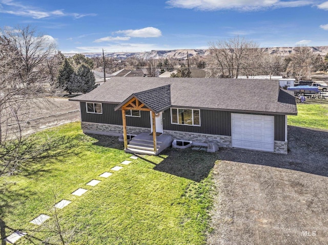 view of front facade with stone siding, roof with shingles, gravel driveway, and a front yard