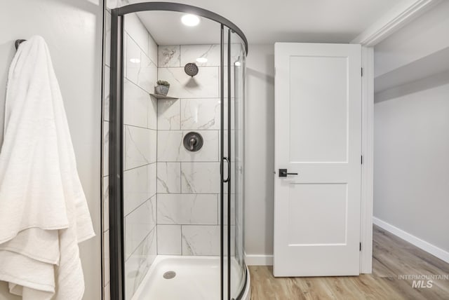 bathroom with a stall shower, baseboards, and wood finished floors