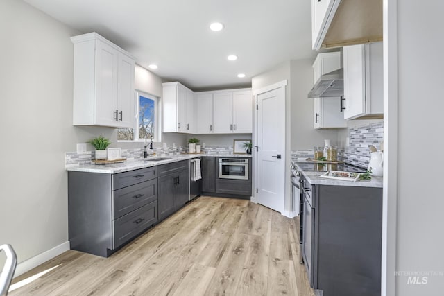 kitchen with gray cabinetry, under cabinet range hood, a sink, white cabinets, and appliances with stainless steel finishes