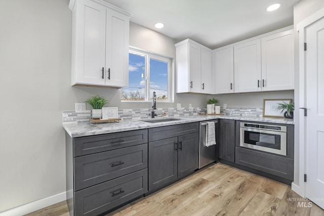 kitchen featuring stainless steel appliances, gray cabinets, a sink, and white cabinets