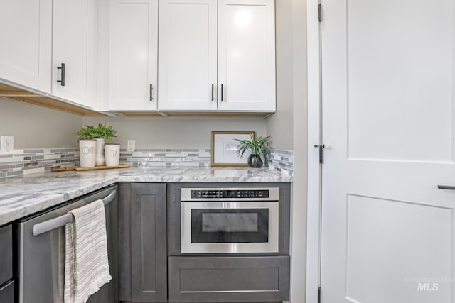 kitchen with stainless steel appliances, white cabinets, and decorative backsplash